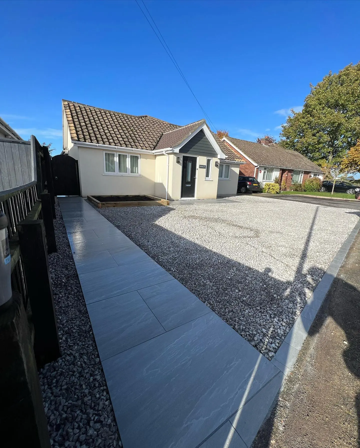 Gravel driveway with porcelain paved path to a bungalow