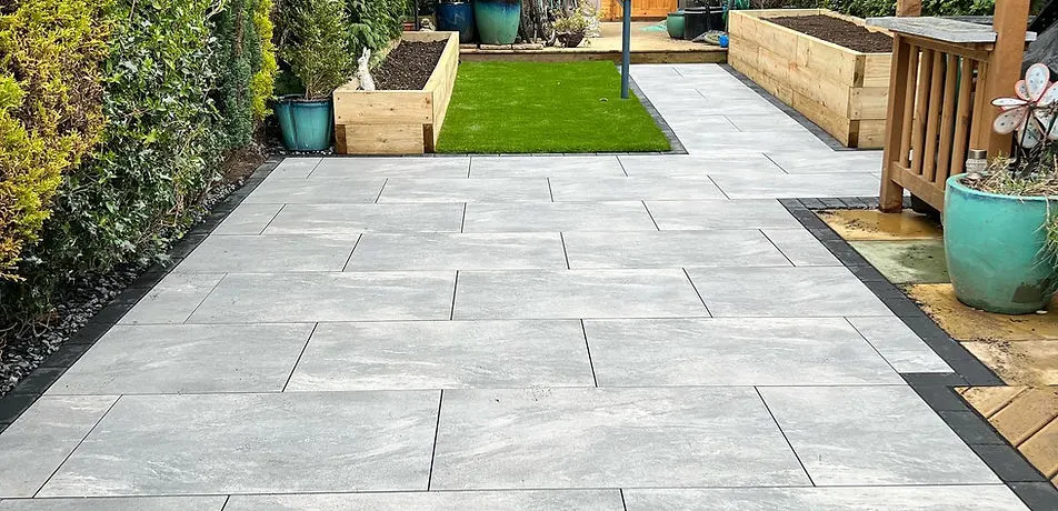Light porcelain patio with sleeper planters and artificial grass