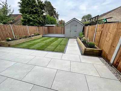 Porcelain patio and path leading to a garden shed with lawn either side